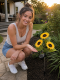 Customer crouched beside her Auré sunflower solar lights in a backyard garden at golden hour